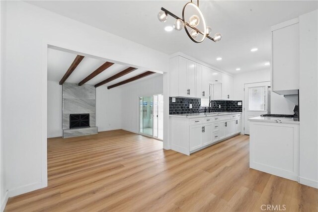 611 S Thorson Ave, Compton, CA 90221 - kitchen with a sink, light countertops, beam ceiling, white cabinetry, and light wood-style flooring