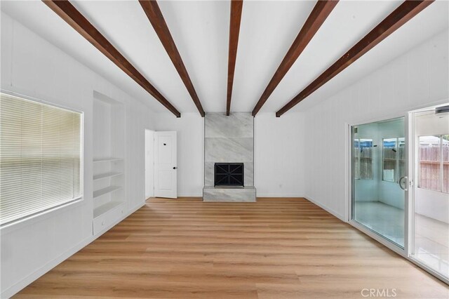 611 S Thorson Ave, Compton, CA 90221 - unfurnished living room with light wood-type flooring, beam ceiling, a high end fireplace, built in features, and baseboards