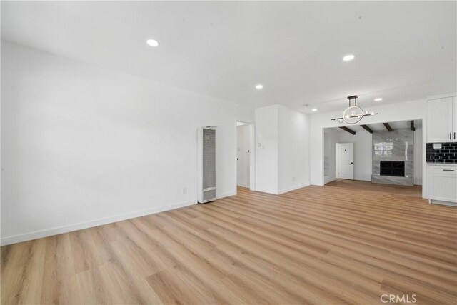 611 S Thorson Ave, Compton, CA 90221 - unfurnished living room featuring a heating unit, light wood-style flooring, a high end fireplace, recessed lighting, and baseboards