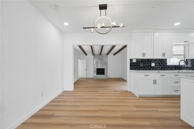 611 S Thorson Ave, Compton, CA 90221 - kitchen with beam ceiling, white cabinets, light wood-style floors, light countertops, and a chandelier