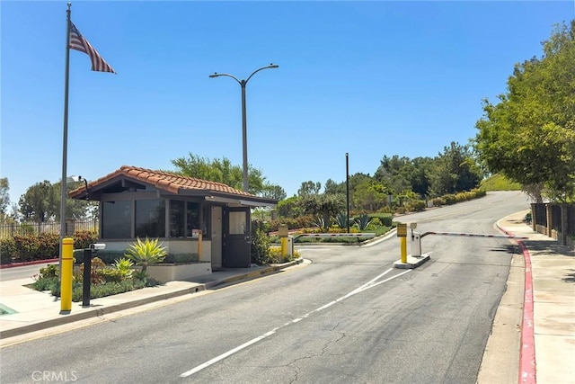 4007 Calle Sonora Oeste Unit 1A, Laguna Woods, CA 92637 - view of asphalt road with curbs, street lights, and a gated entry