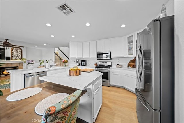 1528 Hendrix Pl, Chula Vista, CA 91911 - kitchen featuring appliances with stainless steel finishes, a peninsula, ceiling fan, a sink, and a tile fireplace