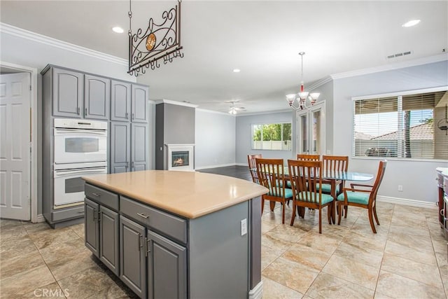967 Hidden Oaks, Beaumont, CA 92223 - kitchen with gray cabinets, white double oven, crown molding, a warm lit fireplace, and a chandelier