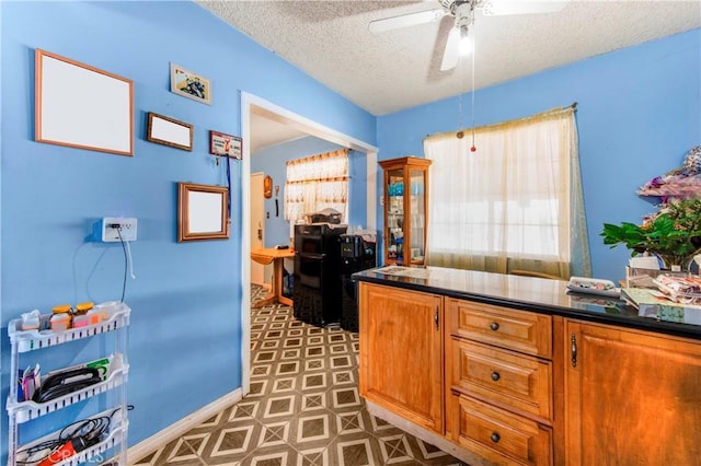 10636 Wolfe Ave, Riverside, CA 92505 - kitchen featuring a textured ceiling, a ceiling fan, dark countertops, brown cabinets, and baseboards
