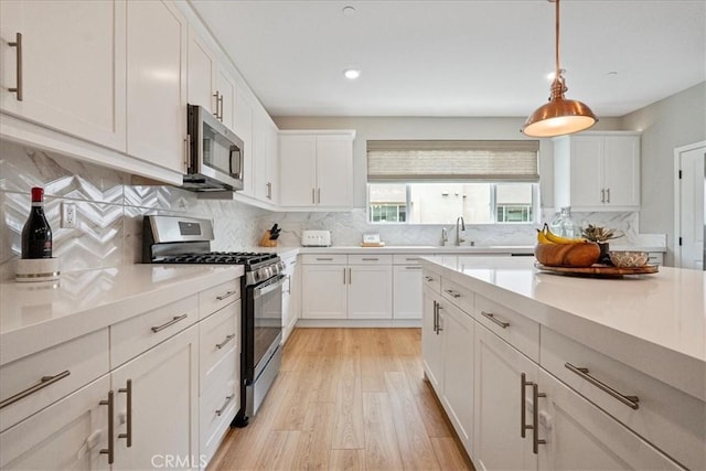3516 Brody Way, Oceanside, CA 92056 - kitchen featuring appliances with stainless steel finishes, light wood finished floors, backsplash, a sink, and white cabinetry