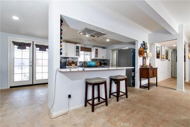 5536 Cahuilla Ave Unit 29, Palms, CA 92277 - kitchen featuring freestanding refrigerator, glass insert cabinets, a peninsula, white cabinets, and a kitchen breakfast bar
