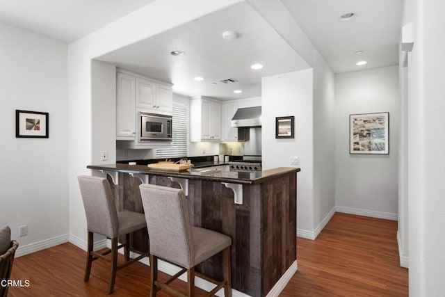433 N Altadena Dr Unit 4, Pasadena, CA 91107 - kitchen with stainless steel microwave, white cabinetry, a breakfast bar, dark countertops, and recessed lighting