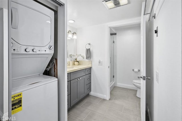 676 Via Alhambra Unit C, Laguna Woods, CA 92637 - laundry area with stacked washing machine and dryer, baseboards, and light tile patterned floors
