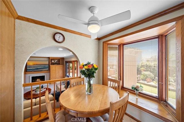 20161 Glacier Cir, Huntington Beach, CA 92646 - dining space featuring a ceiling fan, arched walkways, ornamental molding, and a brick fireplace