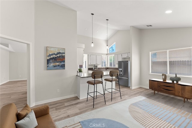 1318 Washington Ave, San Jacinto, CA 92583 - kitchen with high end fridge, high vaulted ceiling, light wood finished floors, a peninsula, and a breakfast bar area