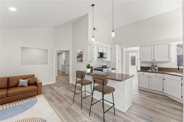 1318 Washington Ave, San Jacinto, CA 92583 - kitchen with high vaulted ceiling, dark countertops, a kitchen bar, and white cabinets