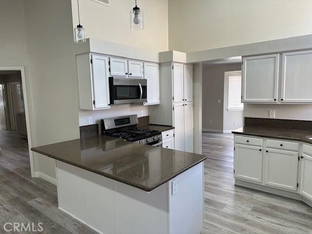 1318 Washington Ave, San Jacinto, CA 92583 - kitchen with appliances with stainless steel finishes, a high ceiling, baseboards, light wood-style floors, and white cabinets