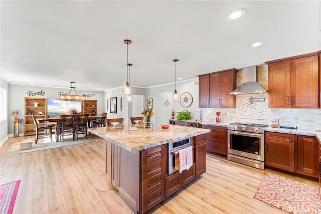 1050 Shelburne Ln, Habra, CA 90631 - kitchen featuring appliances with stainless steel finishes, wall chimney range hood, light wood-style flooring, light stone counters, and hanging light fixtures