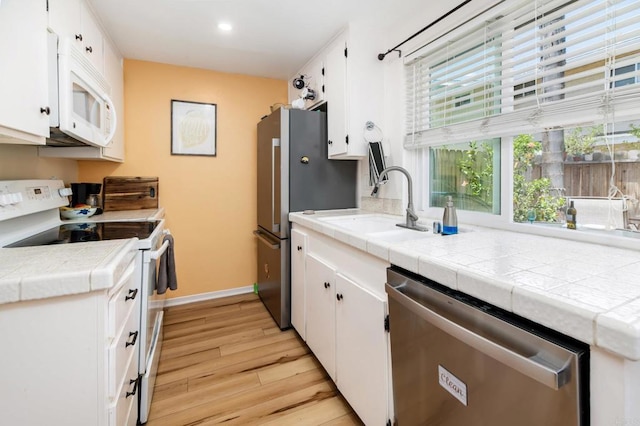 2522 Wanek Rd Unit B, Escondido, CA 92027 - kitchen with appliances with stainless steel finishes, light wood-style flooring, white cabinetry, baseboards, and a sink