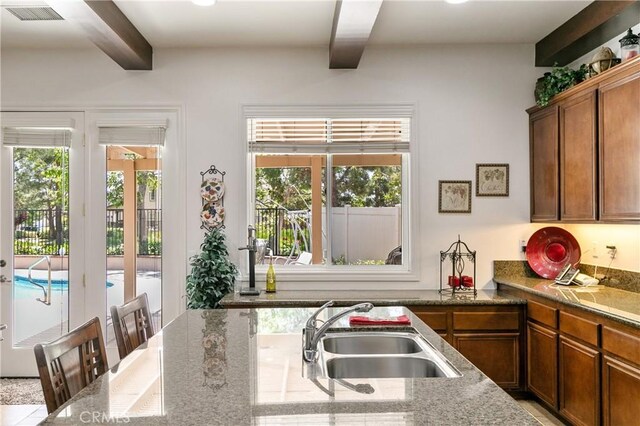 11538 Stoney Brook Ct, Beaumont, CA 92223 - kitchen with a sink, beamed ceiling, light stone counters, and brown cabinetry