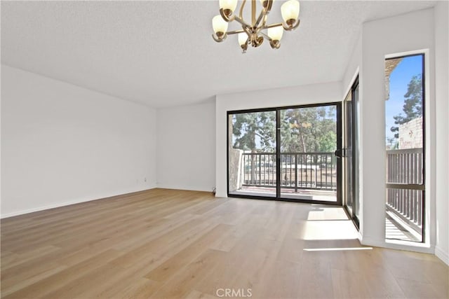 2015 E Broadway Unit 204, Long Beach, CA 90803 - unfurnished room featuring a chandelier, wood finished floors, plenty of natural light, a textured ceiling, and baseboards