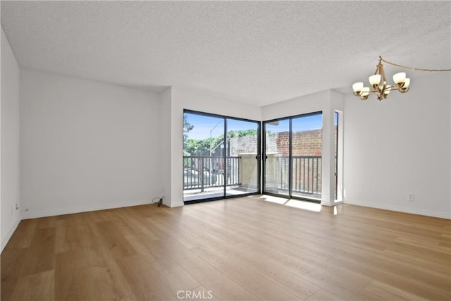 2015 E Broadway Unit 204, Long Beach, CA 90803 - unfurnished room featuring a chandelier, a textured ceiling, light wood-style floors, and baseboards
