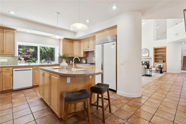 993 Las Palmas Way, San Luis Obispo, CA 93401 - kitchen with built in fridge, white dishwasher, light brown cabinets, a center island with sink, and light tile patterned flooring