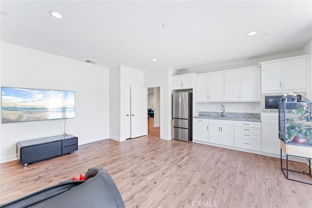 17150 Vita Way, Riverside, CA 92503 - kitchen with freestanding refrigerator, white cabinetry, light wood-style flooring, a sink, and light stone counters