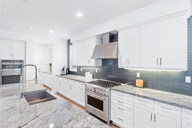17150 Vita Way, Riverside, CA 92503 - kitchen featuring a sink, wall chimney range hood, appliances with stainless steel finishes, tasteful backsplash, and white cabinets