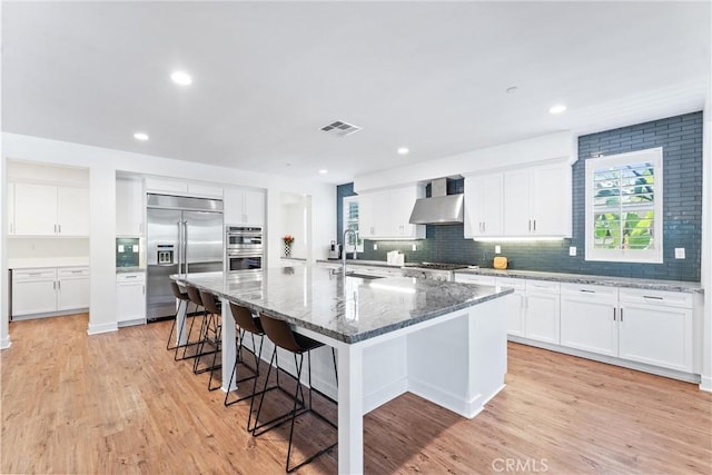 17150 Vita Way, Riverside, CA 92503 - kitchen featuring stainless steel appliances, a sink, wall chimney range hood, a kitchen breakfast bar, and plenty of natural light