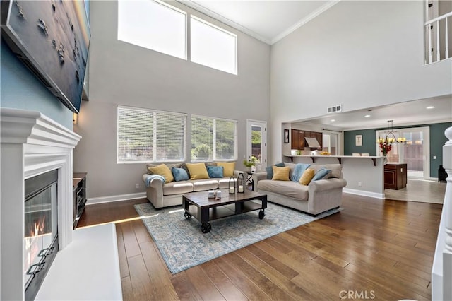 38872 Cherry Point Ln, Murrieta, CA 92563 - living room with ornamental molding, a glass covered fireplace, baseboards, dark wood-style floors, and a chandelier