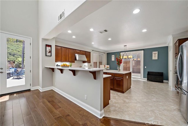 38872 Cherry Point Ln, Murrieta, CA 92563 - kitchen with under cabinet range hood, a peninsula, light countertops, crown molding, and a chandelier