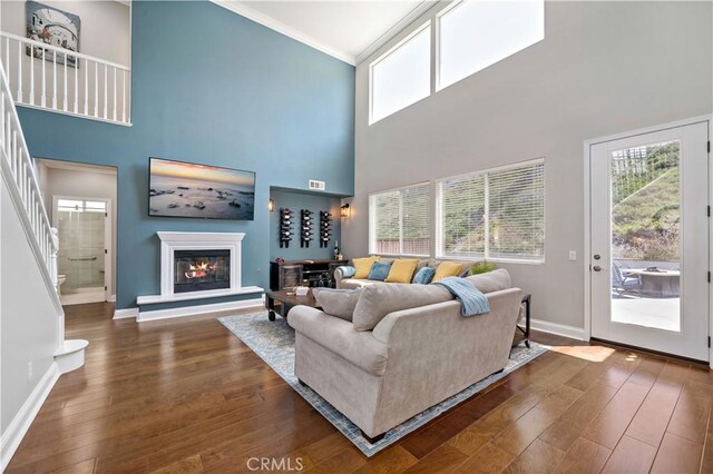 38872 Cherry Point Ln, Murrieta, CA 92563 - living room featuring baseboards, crown molding, plenty of natural light, a glass covered fireplace, and a towering ceiling