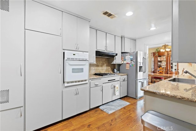 945 W Bonnie Brae Ct, Ontario, CA 91762 - kitchen featuring oven, stainless steel fridge, under cabinet range hood, a sink, and backsplash