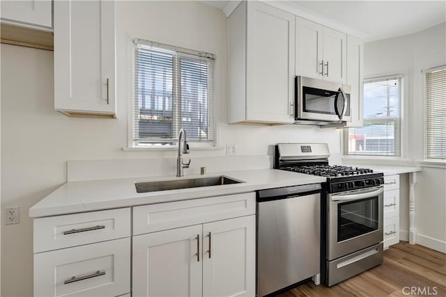 4427 Exposition Blvd, Los Angeles, CA 90016 - kitchen with appliances with stainless steel finishes, a sink, light countertops, wood finished floors, and white cabinets