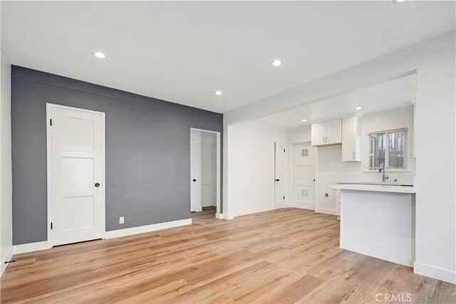 4427 Exposition Blvd, Los Angeles, CA 90016 - unfurnished living room featuring light wood-style flooring, recessed lighting, baseboards, and a sink
