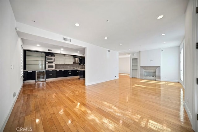 132 S Crescent Dr Unit 202, Beverly Hills, CA 90212 - unfurnished living room with wine cooler, baseboards, light wood finished floors, recessed lighting, and a bar