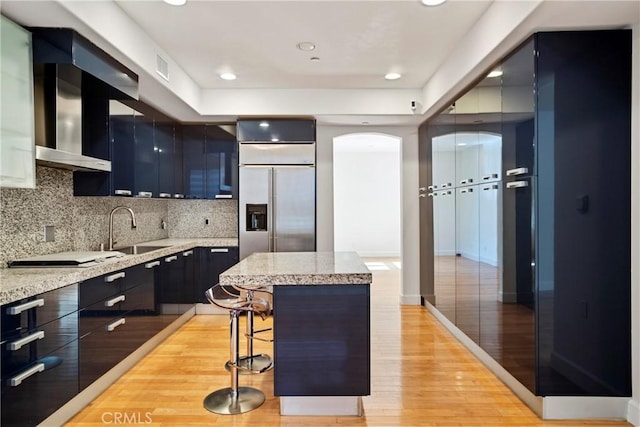 132 S Crescent Dr Unit 202, Beverly Hills, CA 90212 - kitchen featuring a kitchen island, light wood finished floors, a breakfast bar, backsplash, and built in refrigerator