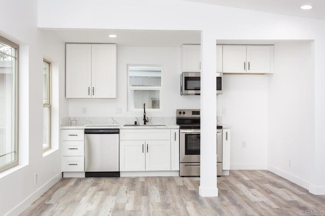 12049 Coping Pl, Lakeside, CA 92040 - kitchen featuring appliances with stainless steel finishes, a sink, light wood-style flooring, baseboards, and white cabinetry