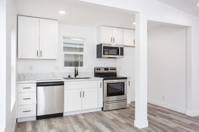 12049 Coping Pl, Lakeside, CA 92040 - kitchen with appliances with stainless steel finishes, a sink, light wood-style floors, white cabinetry, and recessed lighting