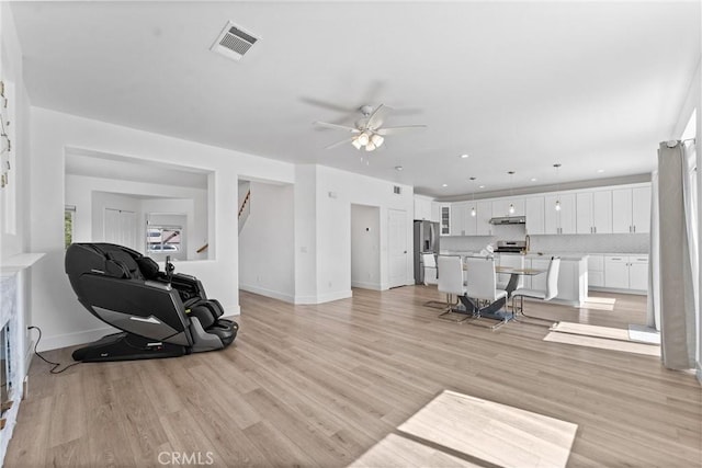 8798 Crest View Dr, Corona, CA 92883 - living room with ceiling fan, light wood-style floors, baseboards, and stairs