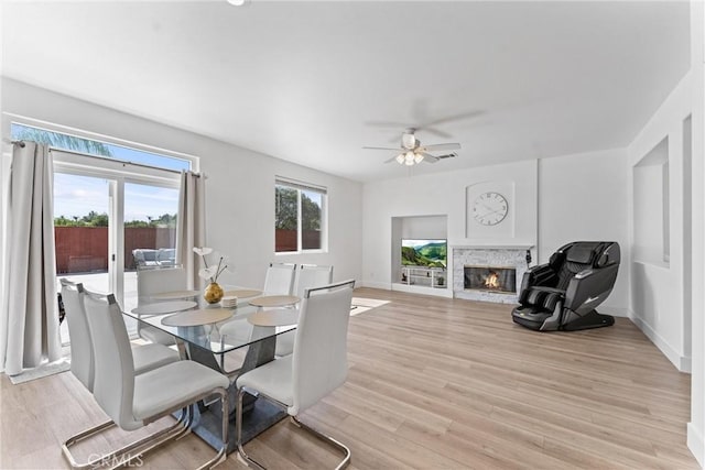 8798 Crest View Dr, Corona, CA 92883 - dining space with a glass covered fireplace, ceiling fan, light wood-style flooring, and baseboards