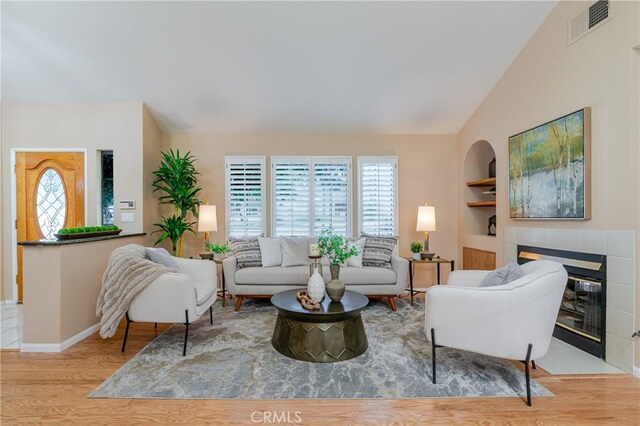 1049 Fairview Ave Unit 5, Arcadia, CA 91007 - living room with wood finished floors, built in shelves, vaulted ceiling, baseboards, and a tiled fireplace