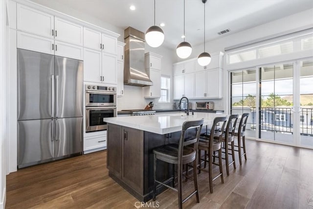 4029 Bernardo Dr, San Luis Obispo, CA 93401 - kitchen featuring appliances with stainless steel finishes, wall chimney range hood, dark wood-style floors, white cabinetry, and recessed lighting