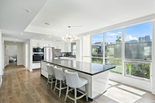 510 First Ave Unit 402, San Diego, CA 92101 - kitchen with stainless steel appliances, dark countertops, a chandelier, white cabinets, and decorative backsplash