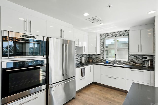 510 First Ave Unit 402, San Diego, CA 92101 - kitchen with appliances with stainless steel finishes, a sink, dark countertops, backsplash, and white cabinetry