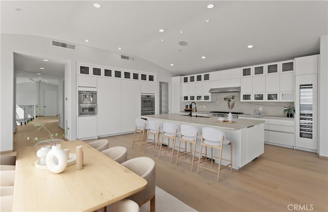 31 N Vista De Catalina, Laguna Beach, CA 92651 - kitchen with a sink, decorative backsplash, lofted ceiling, recessed lighting, and an island with sink