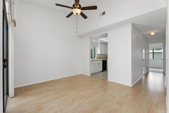 8933 Yolo Cir Unit 1308-A, Huntington Beach, CA 92646 - unfurnished living room featuring ceiling fan, light wood finished floors, baseboards, and a high ceiling