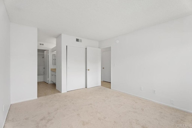 8933 Yolo Cir Unit 1308-A, Huntington Beach, CA 92646 - unfurnished bedroom with light carpet, ensuite bathroom, baseboards, and a textured ceiling