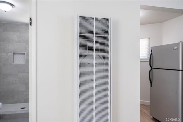 407 W 107th St, Los Angeles, CA 90003 - detailed view of freestanding refrigerator, a heating unit, baseboards, and wood finished floors