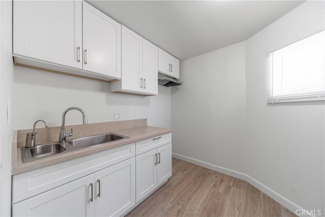 407 W 107th St, Los Angeles, CA 90003 - kitchen featuring a sink, light wood-type flooring, white cabinetry, baseboards, and light countertops