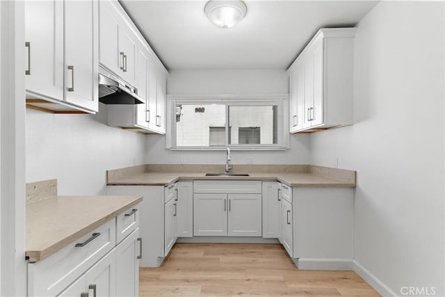 407 W 107th St, Los Angeles, CA 90003 - kitchen with a sink, under cabinet range hood, white cabinets, light wood-type flooring, and light countertops