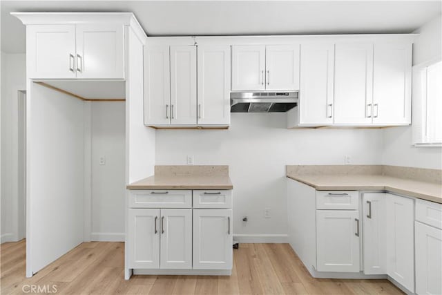 407 W 107th St, Los Angeles, CA 90003 - kitchen with under cabinet range hood, light wood finished floors, white cabinets, and baseboards