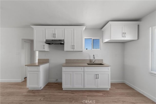 407 W 107th St, Los Angeles, CA 90003 - kitchen with under cabinet range hood, a sink, white cabinets, and plenty of natural light