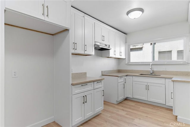 407 W 107th St, Los Angeles, CA 90003 - kitchen featuring a sink, under cabinet range hood, light wood finished floors, white cabinetry, and light countertops
